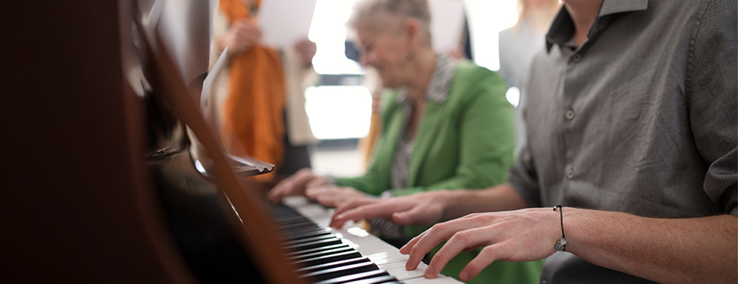 Image of two people's hands playing a piano together